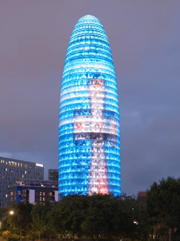 Torre Glòries iluminada em Barcelona para dar as boas-vindas ao Papa Leão XIV, com uma imagem inspirada na cruz da Torre de Jesus da Sagrada Família.